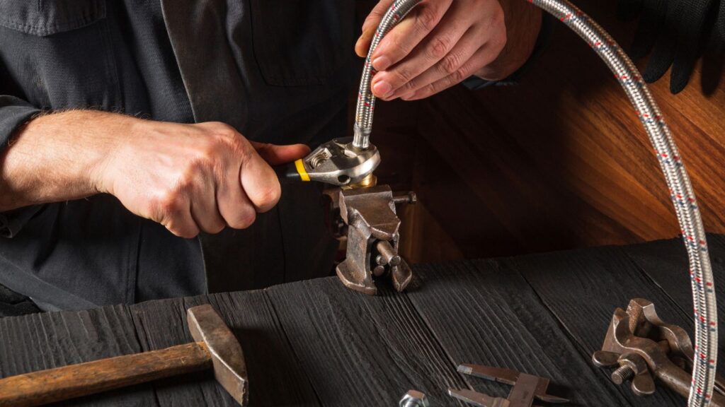 A plumber fixing a high pressure hose.