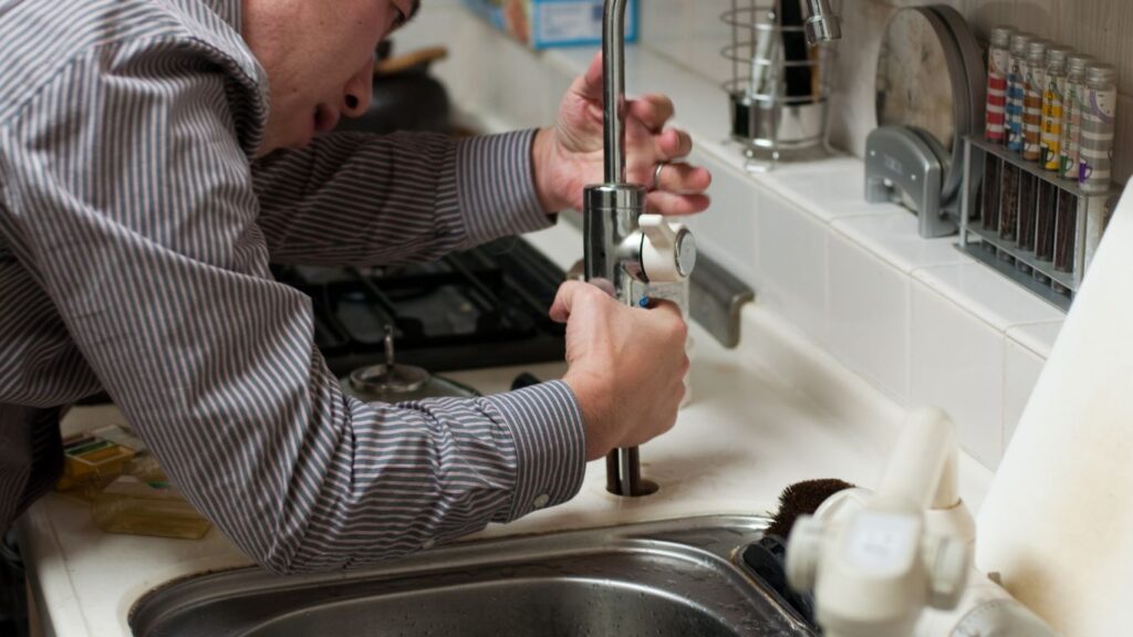 A plumber repairing the sink.