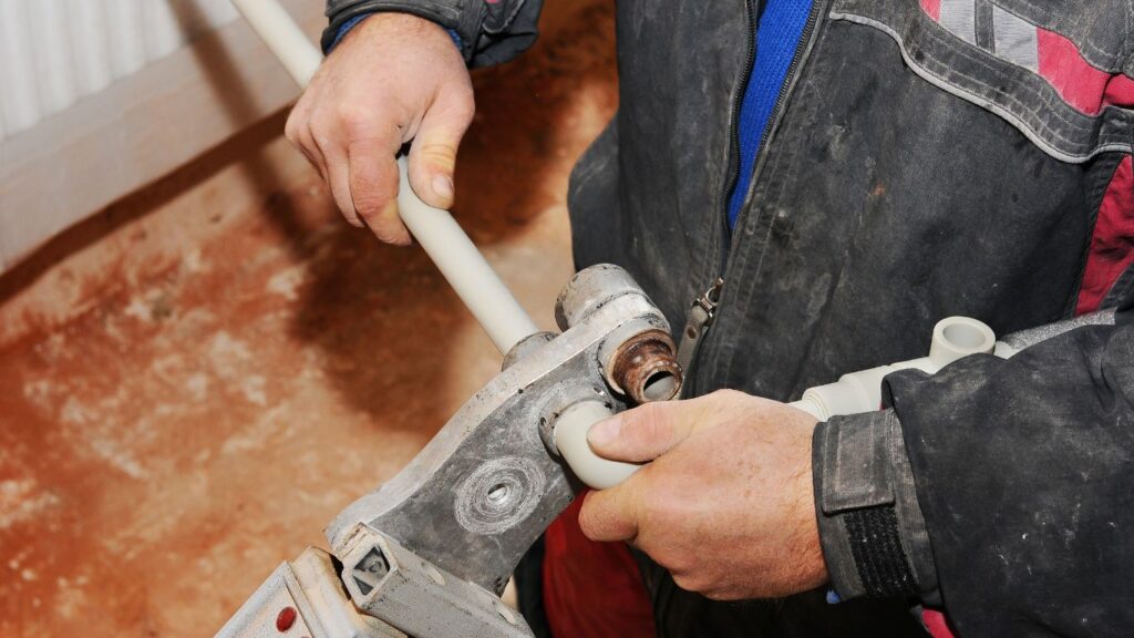 A plumber soldering a plastic pipes.